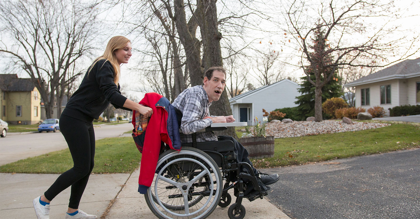 A caregiver pushing an adult with disabilities in a wheelchair.