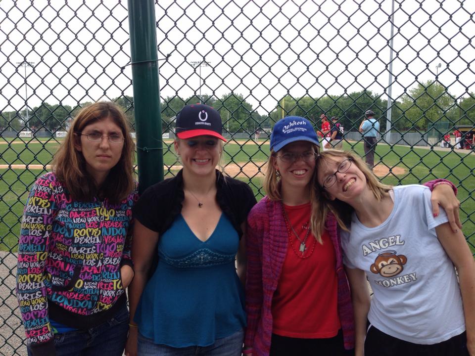 Four people smiling outside of a baseball park.