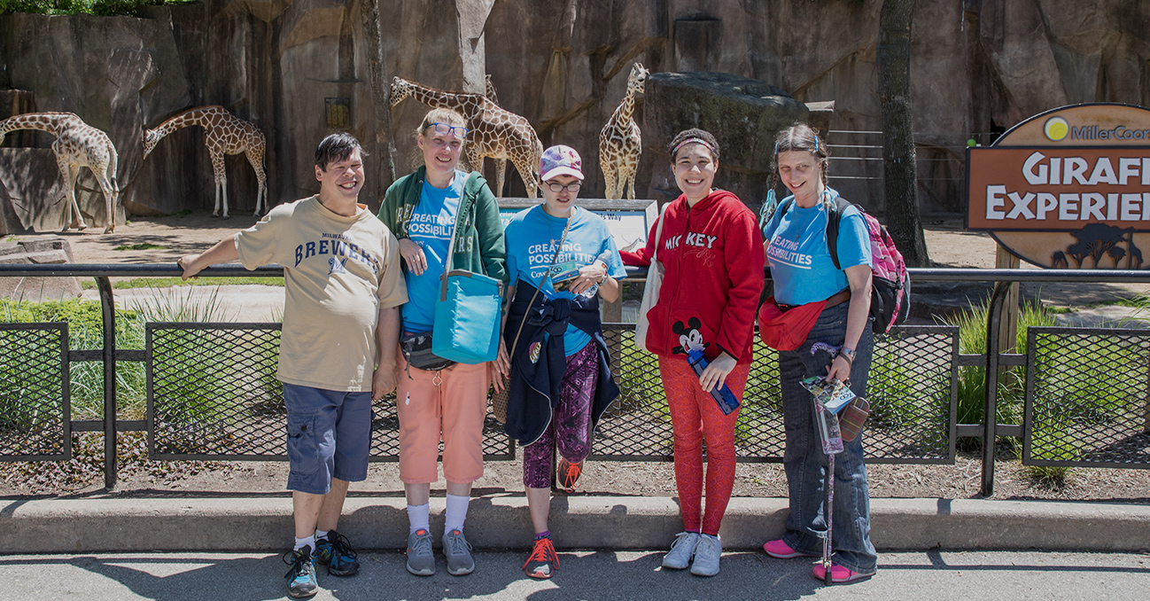 Covey clients smiling with giraffes at the zoo.