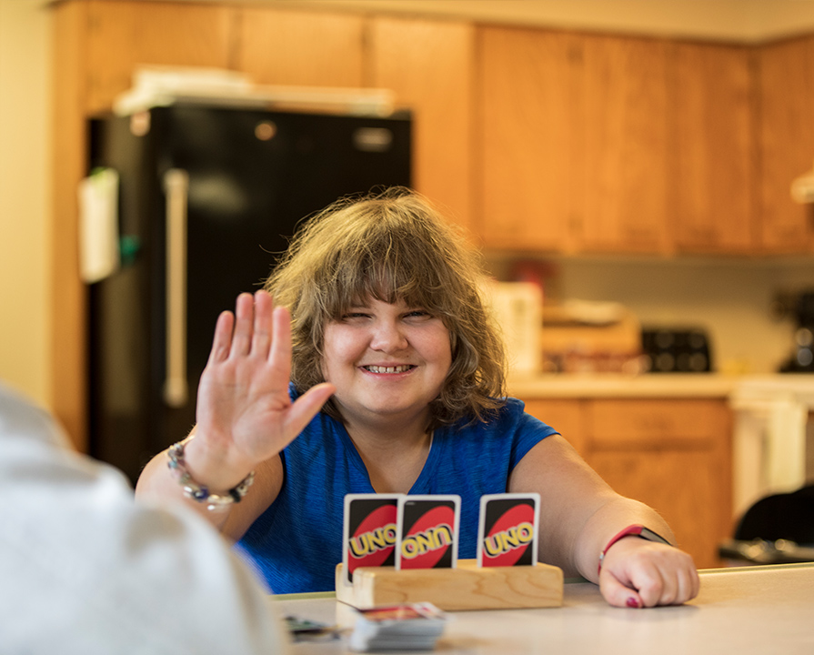 A girl holding up her hand while playing uno.