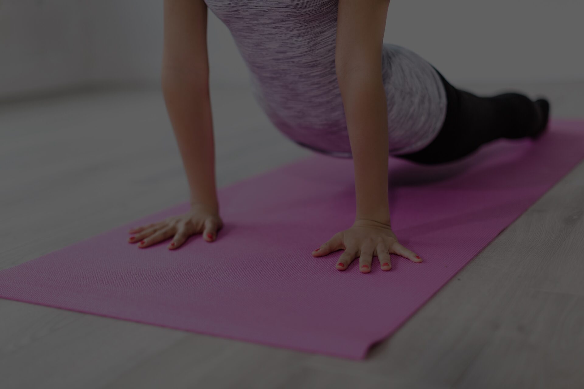 A girl stretching on a pink yoga mat.