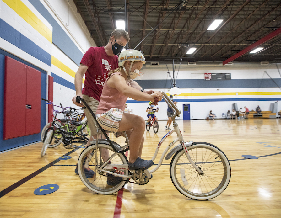 A girl with disabilities getting help on a bike.