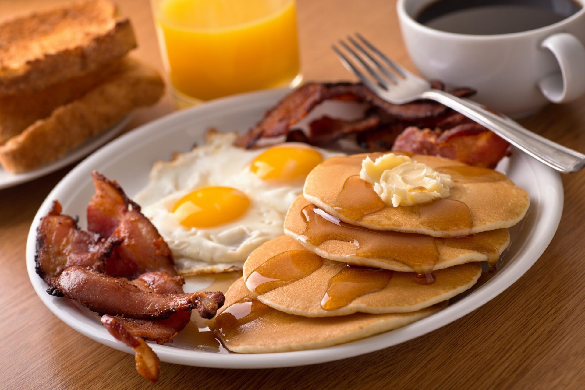 A plate of pancakes, eggs, and bacon.