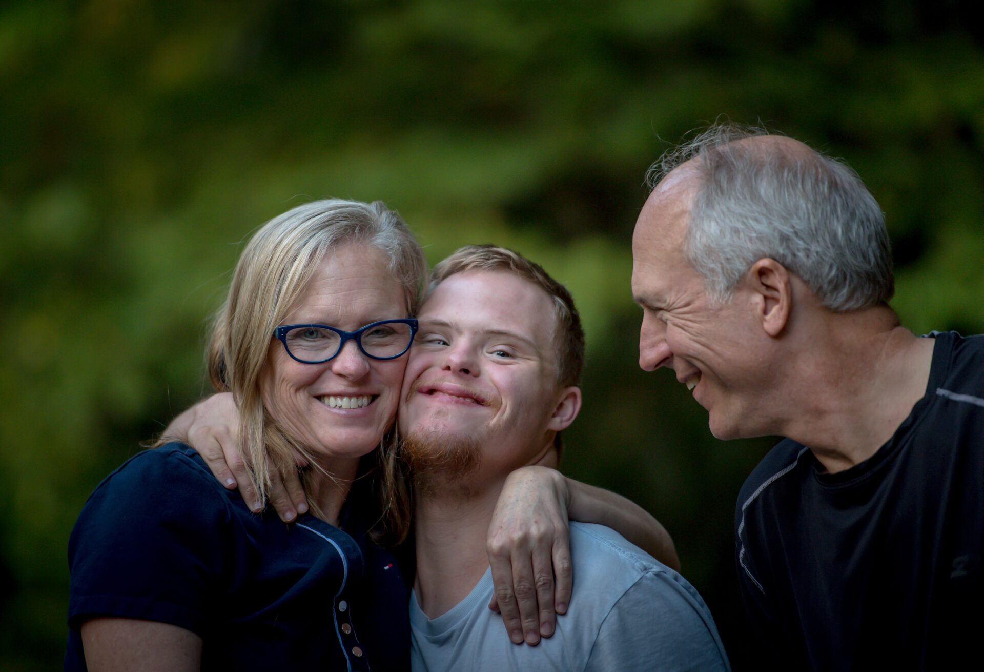 A kid with autism smiling with his parents.