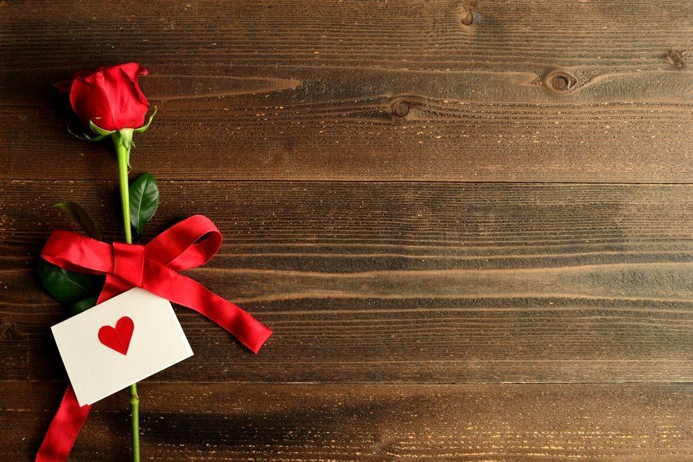 A single rose against a wooden background.