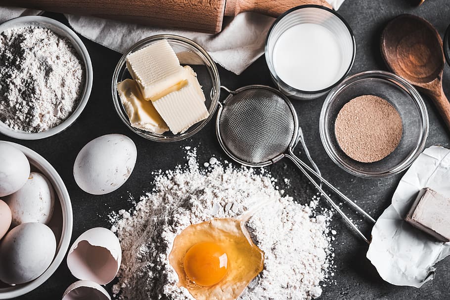 A kitchen table with flour, eggs, and other baking supplies on it.